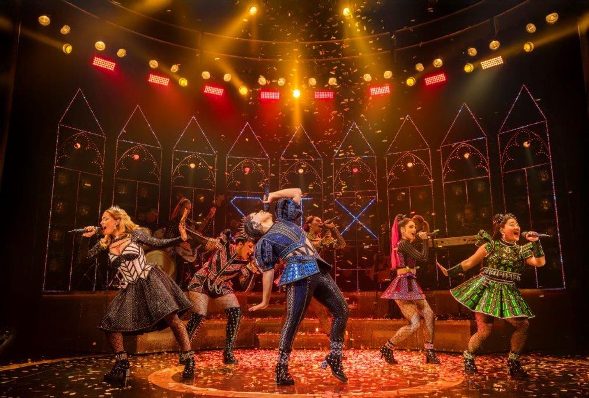 Six people stand on stage posing.