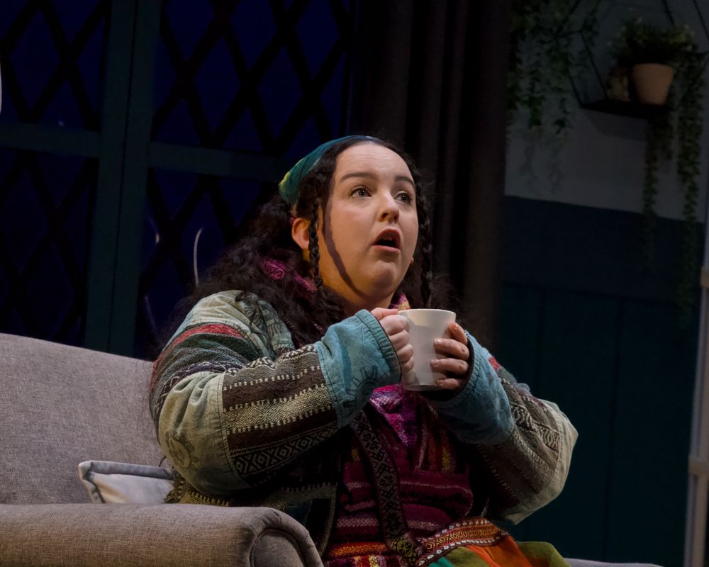 A person is sat on a sofa holding a cup with both hands