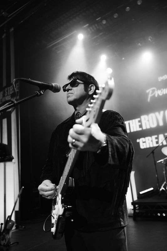 A black and white image of a person playing guitar.