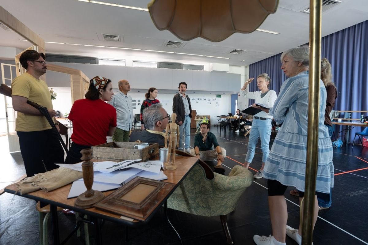 A group of people stood in a living room type setting rehearsing for The Hollow