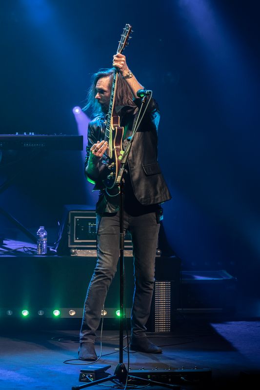 A person in a black leather jacket plays guitar.