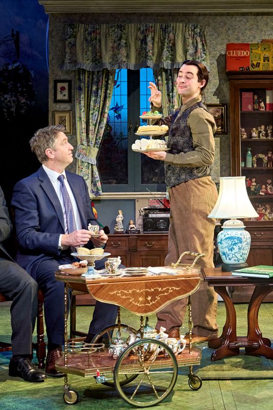 A person stands offering out an afternoon tea selection.