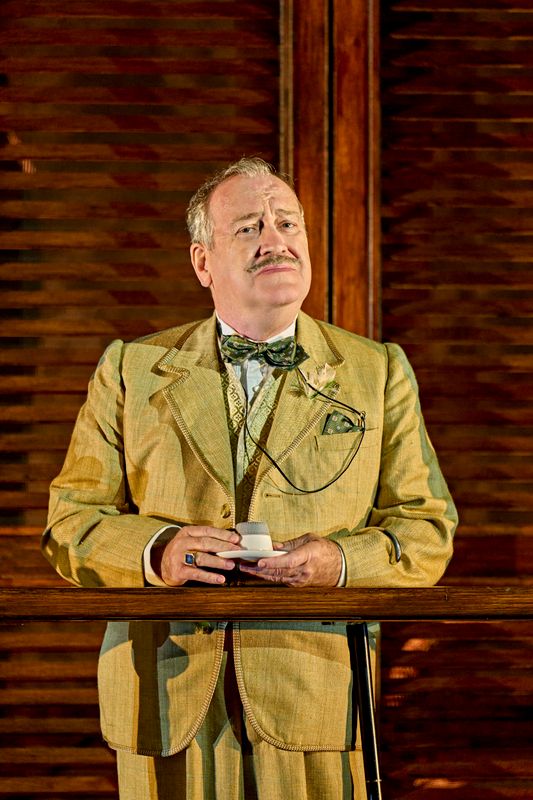 A person in a gold coloured suit drinks a beverage.