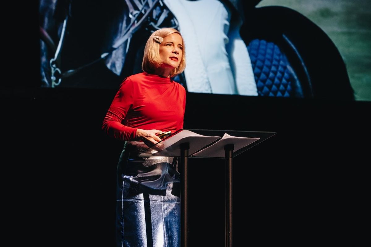 Lucy Worsley talking on stage. She is wearing a red top and a silver pencil skirt.