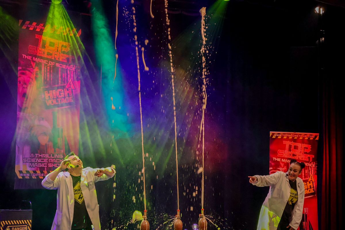 Three coca cola bottles shoot liquid into the air soaking a person below.
