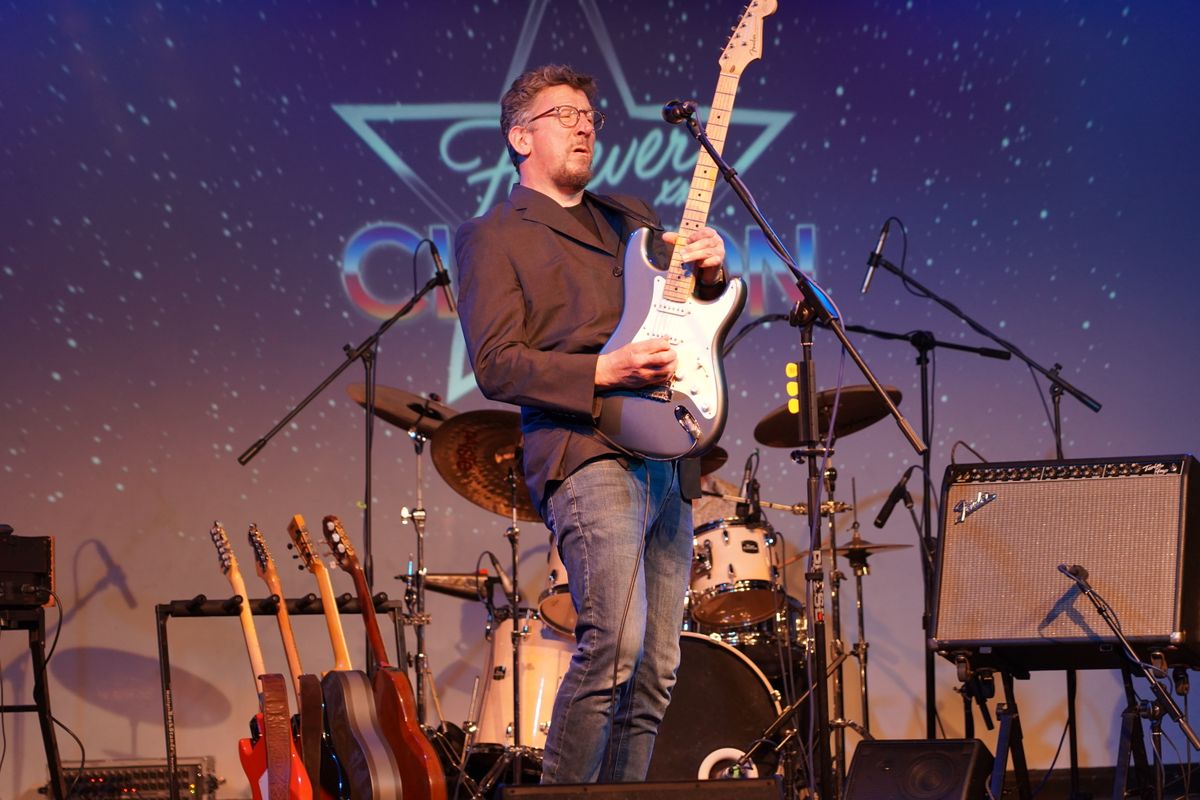 A person plays a blue electric guitar on stage.