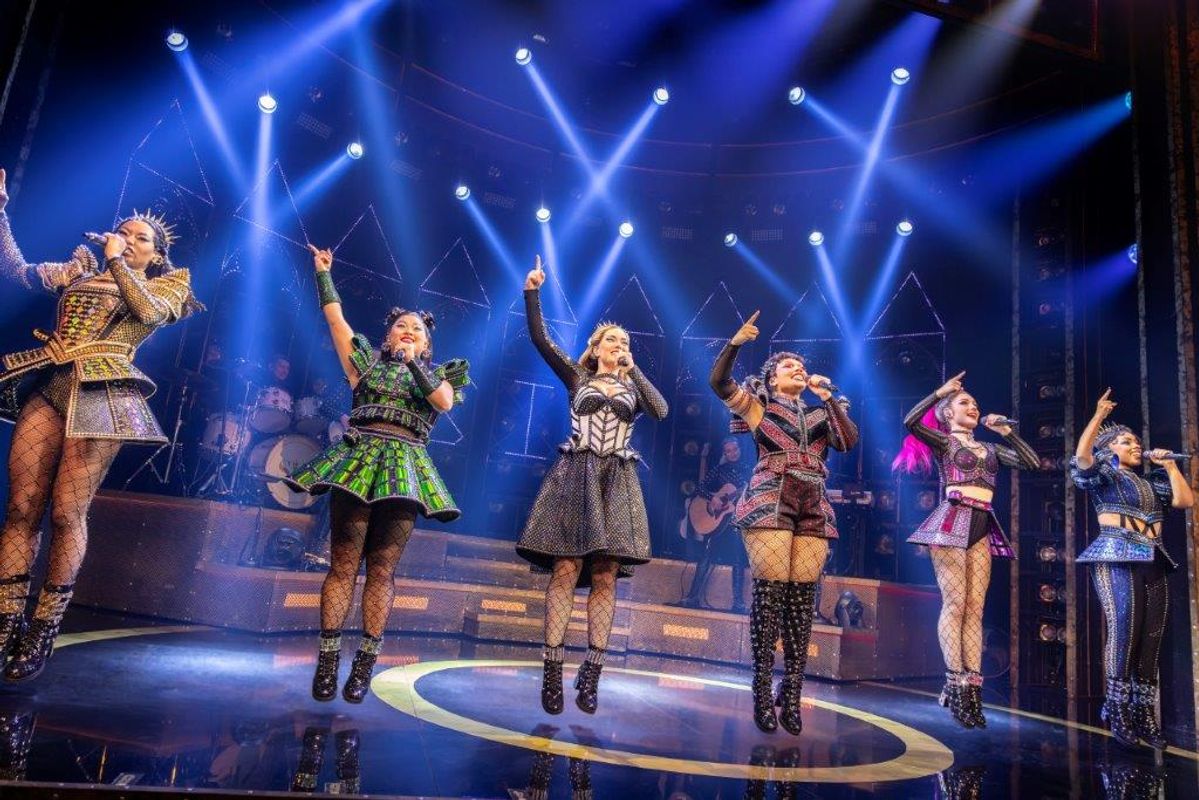 Six people jump in the air with their right arm raised.