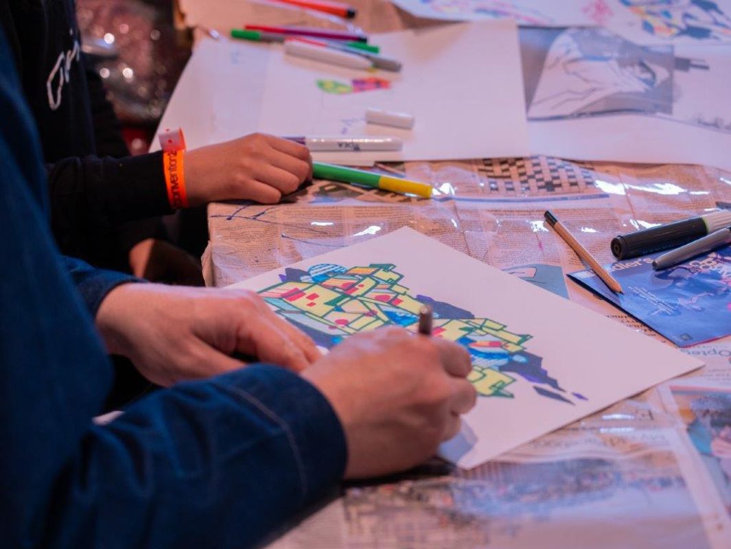 A group of people use felt tip pens to colour in some artwork.