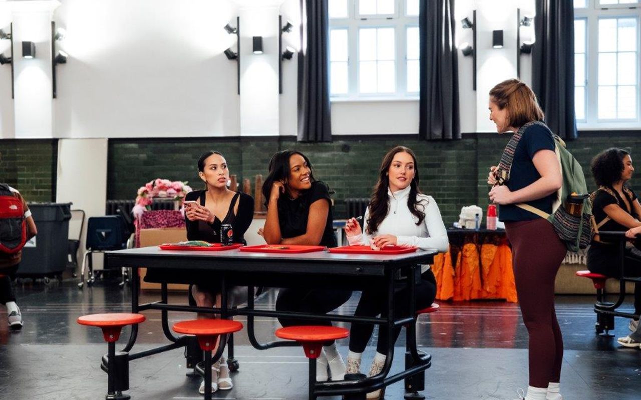 Three people are sat at a dinner table and someone is stood at the end talking to them