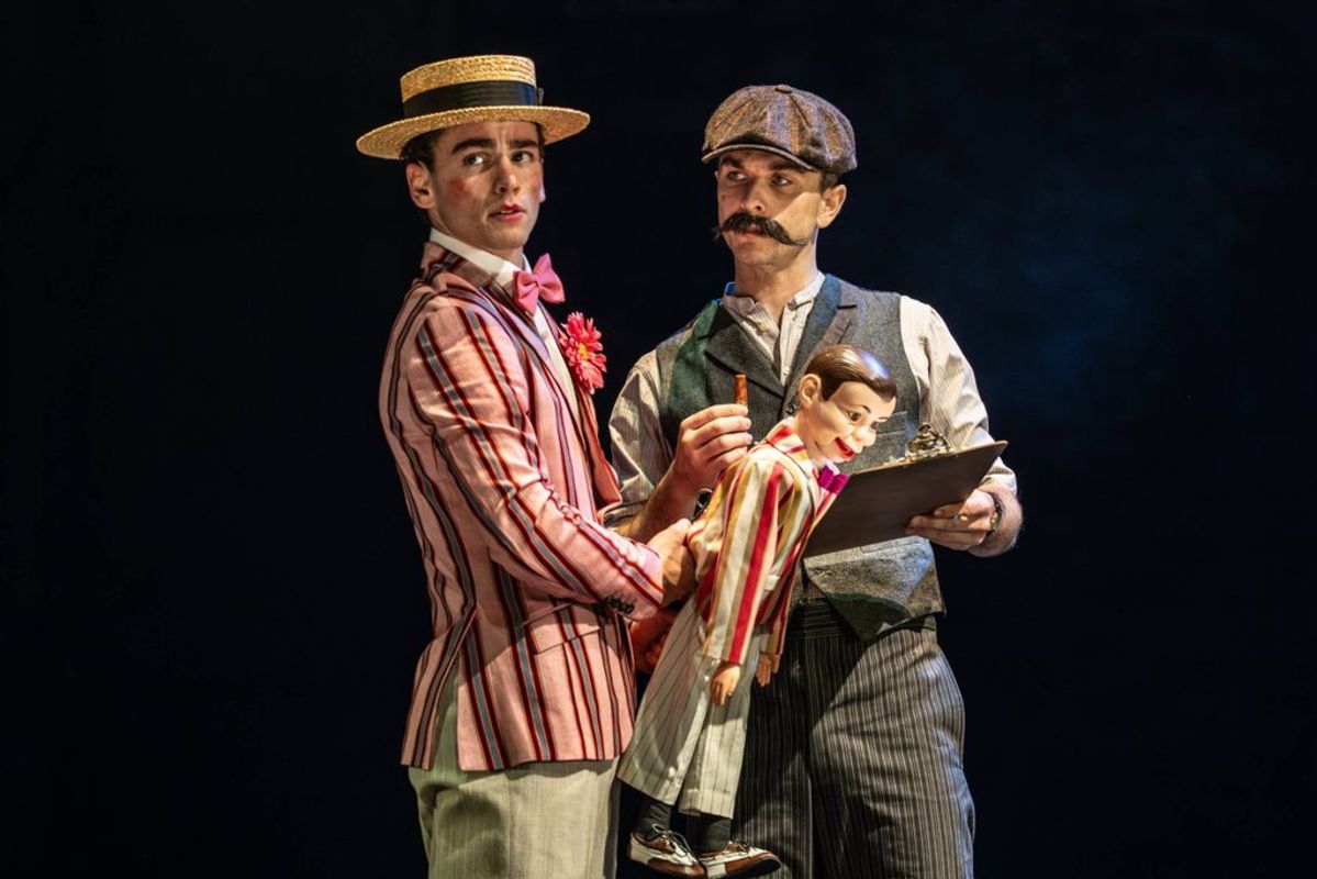 Two people stand on stage with a dummy.