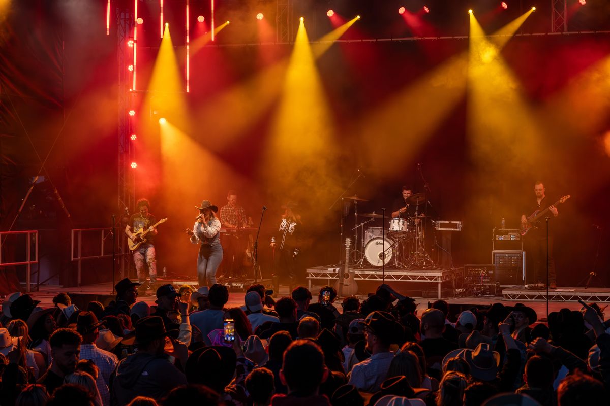 The band perform on stage surrounded by red and orange lights.