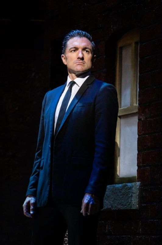 A man in a suit looks on with a serious look on his face