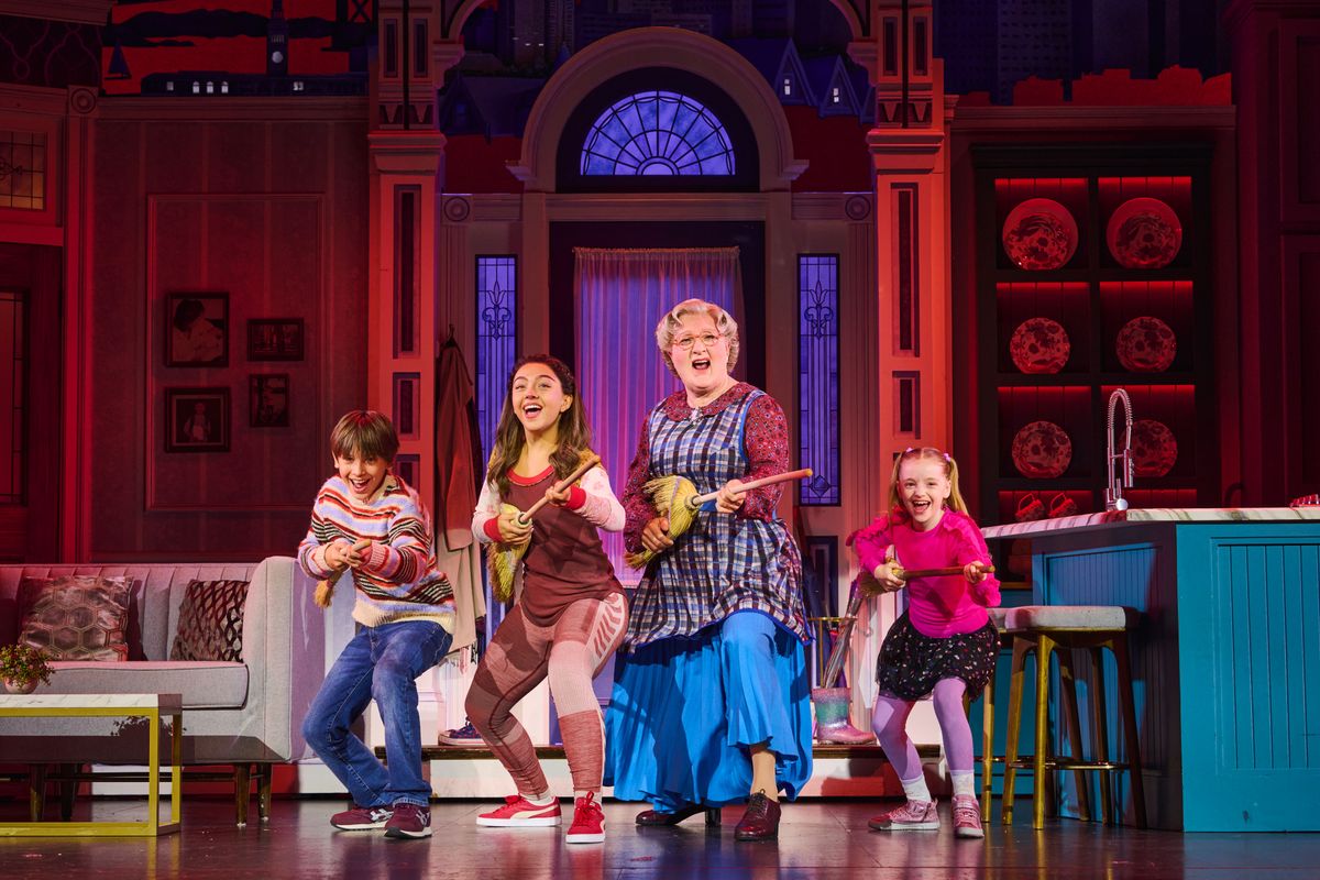 Mrs Doubtfire and the three children stand centre stage playing the brooms as guitars.