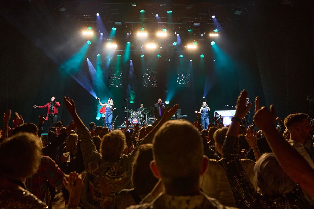 An audience clap with their hands above their head.