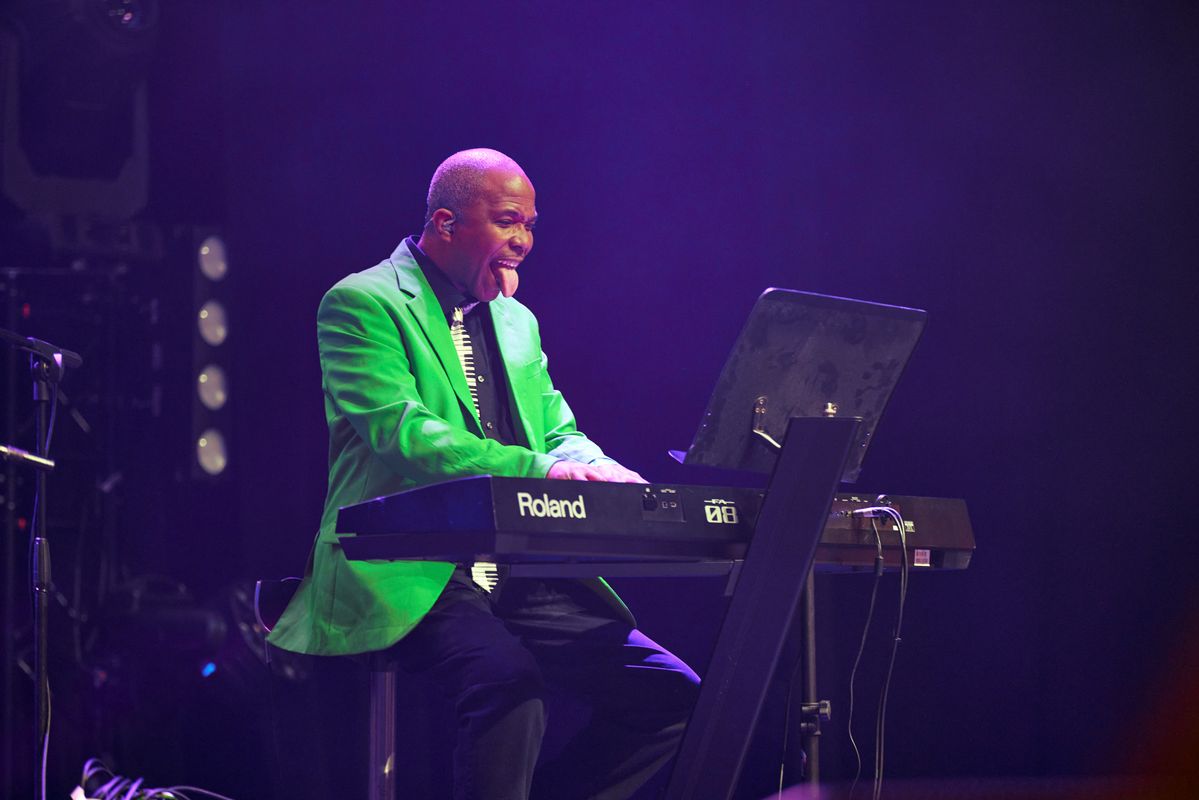 A person wearing a green blazer plays the keyboard.