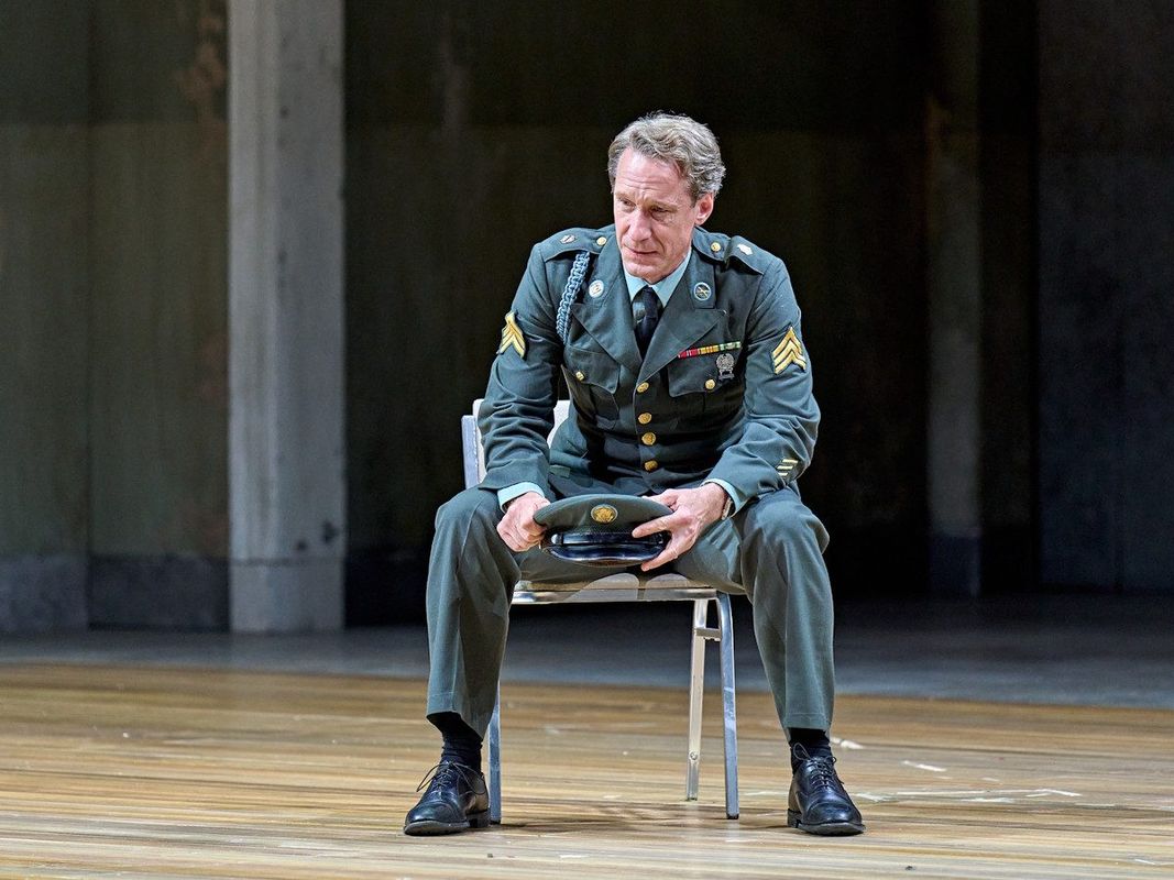 A general is sat on a seat holding their hat