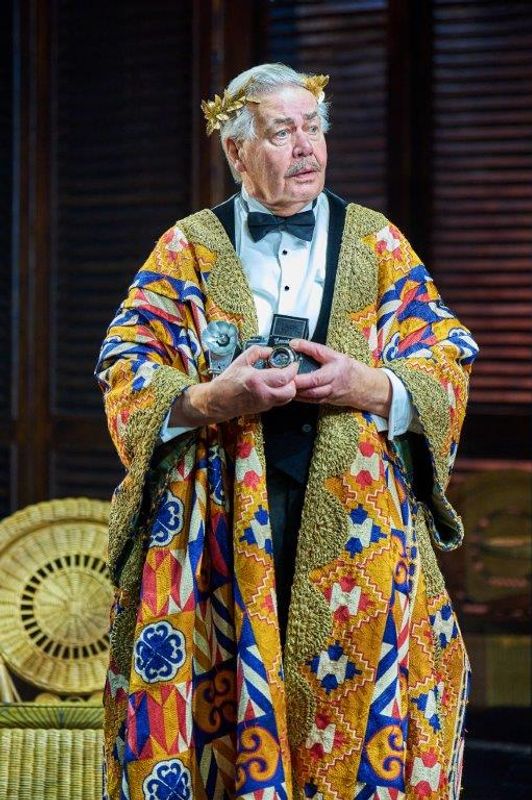 A person stood alone wearing a colourful coat and they have their hands to their waist