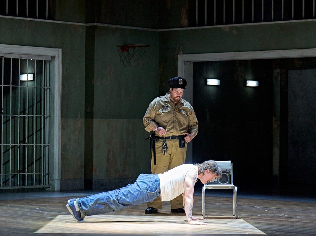 Prison guard is watching an inmate do push ups