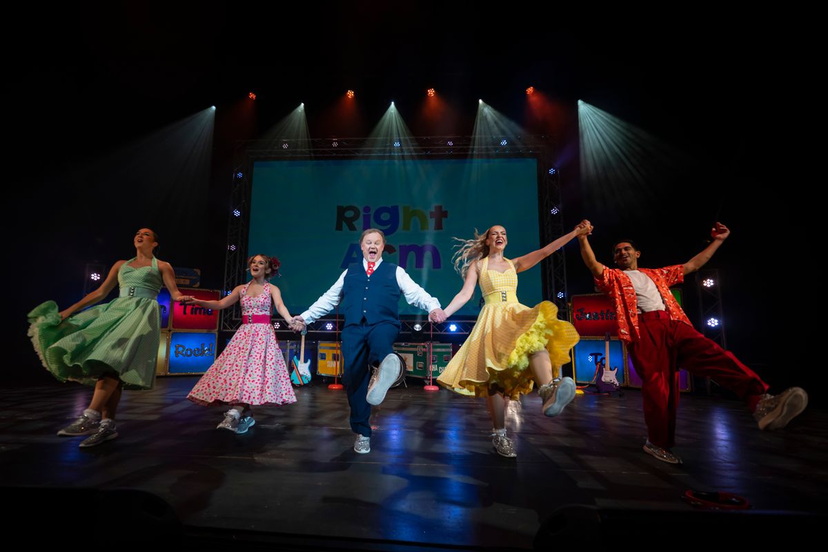 Justin and cast members all hold hands and kick their left leg out.