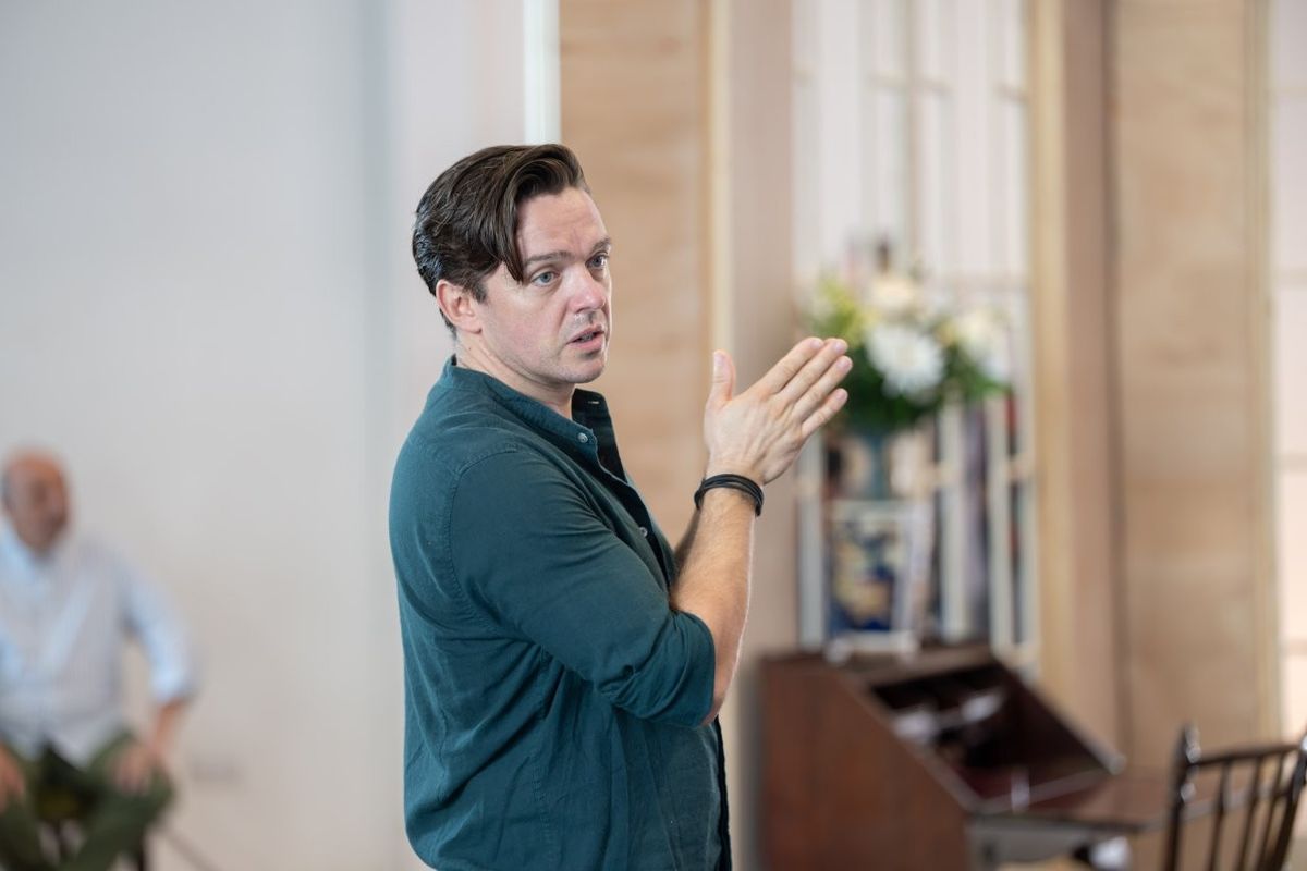 A man has his hand pointing away from him as he looks off camera