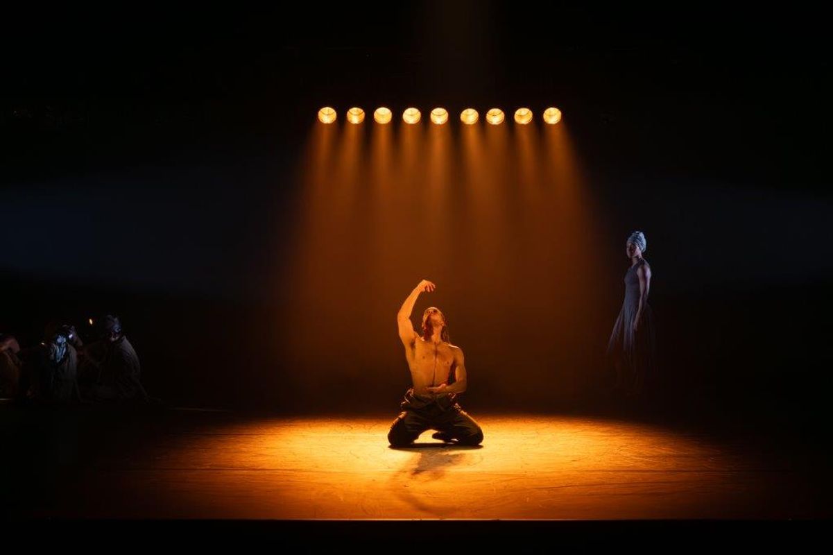 Dancer on stage with a spot light on them, they are kneeling on the floor