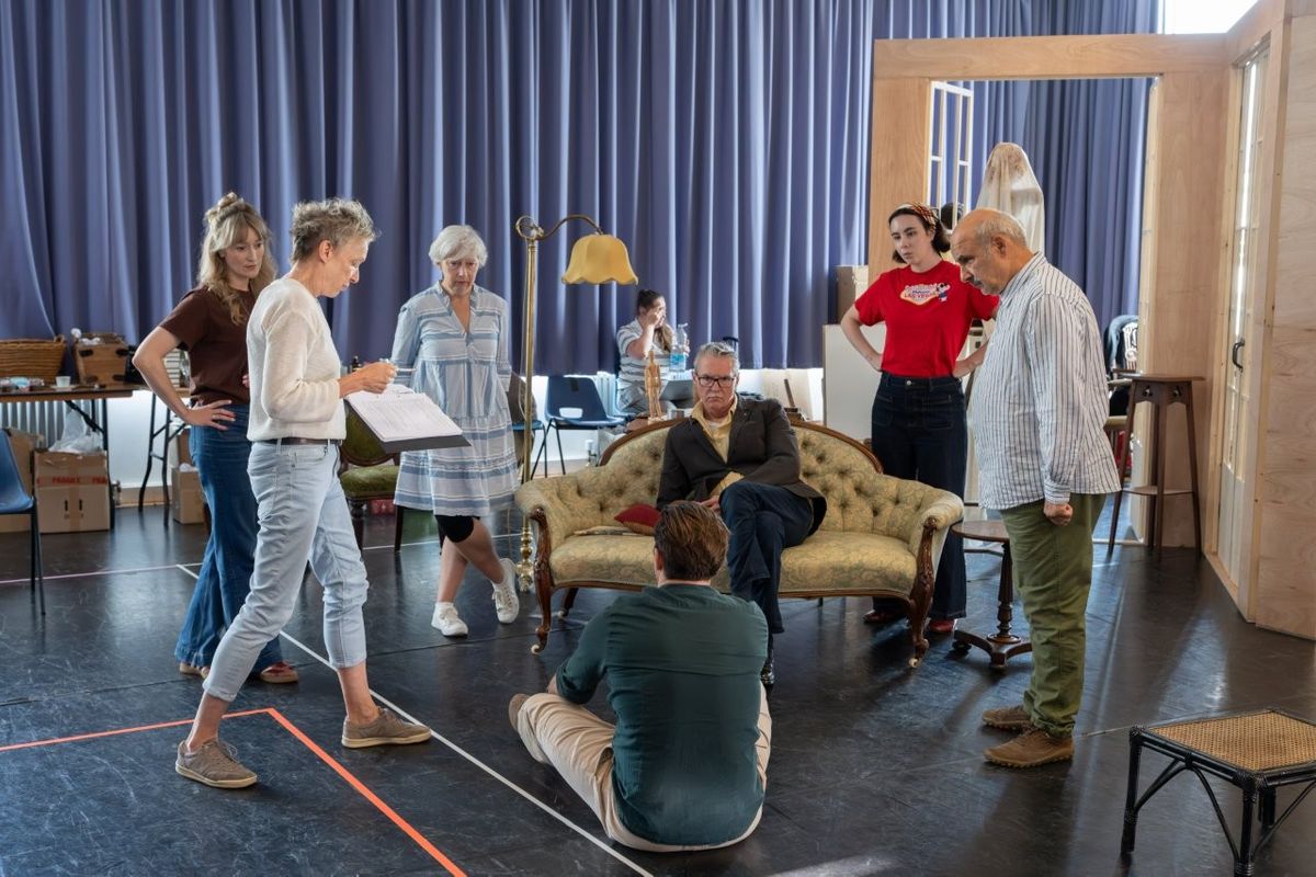 A group of people stood in a living room type setting rehearsing for The Hollow
