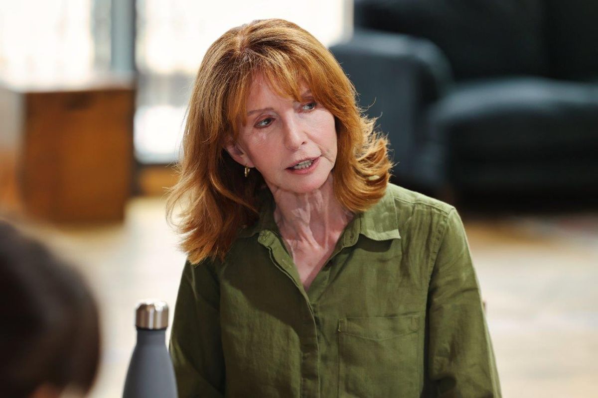A woman in a green shirt looks away at something off camera