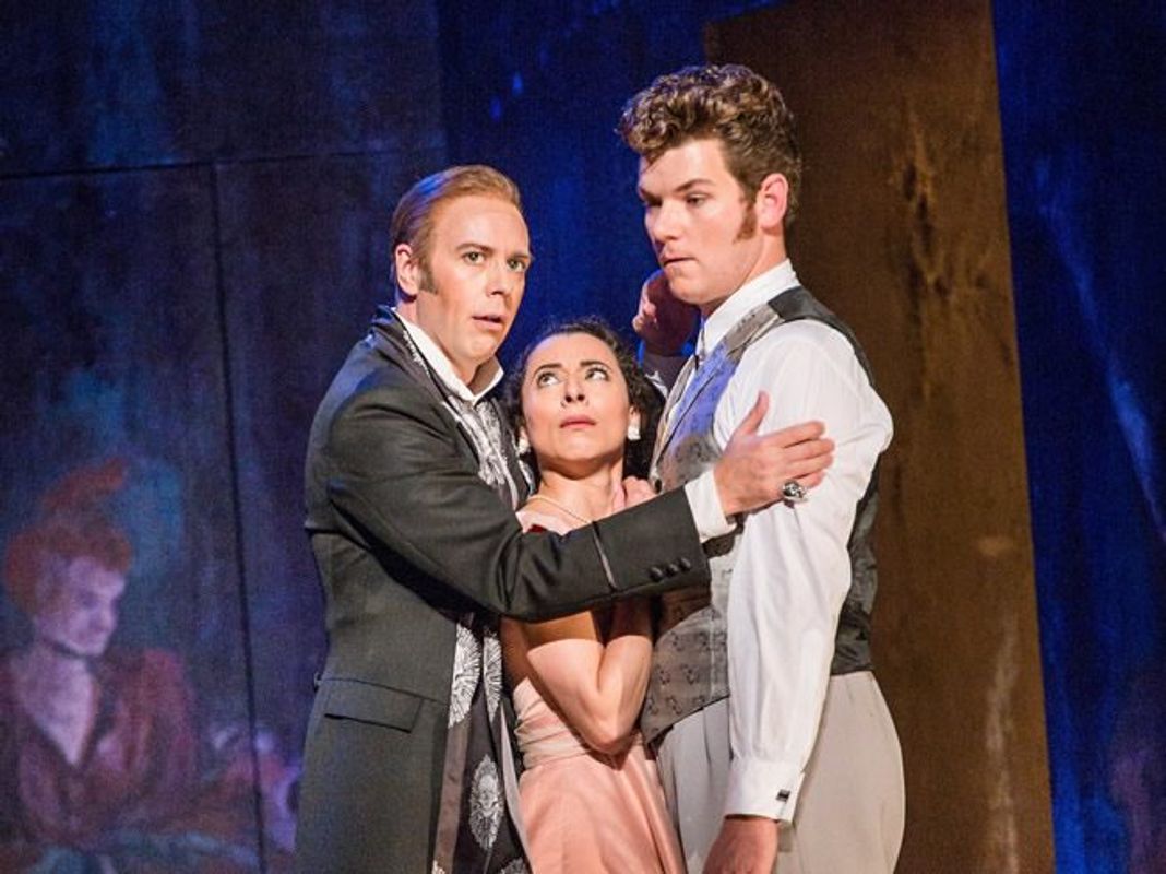 There is a woman in between two men, the woman is looking up at one of the men