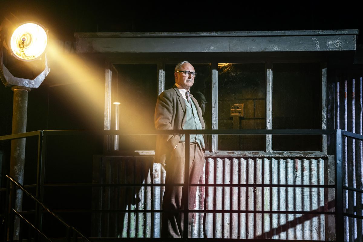 A person stands on a walkway lit by a spotlight.