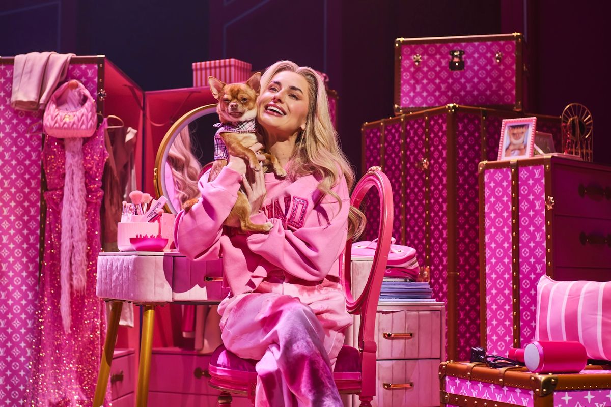 Amber Davis as Elle holding a small dog, sitting down in pink pyjamas.