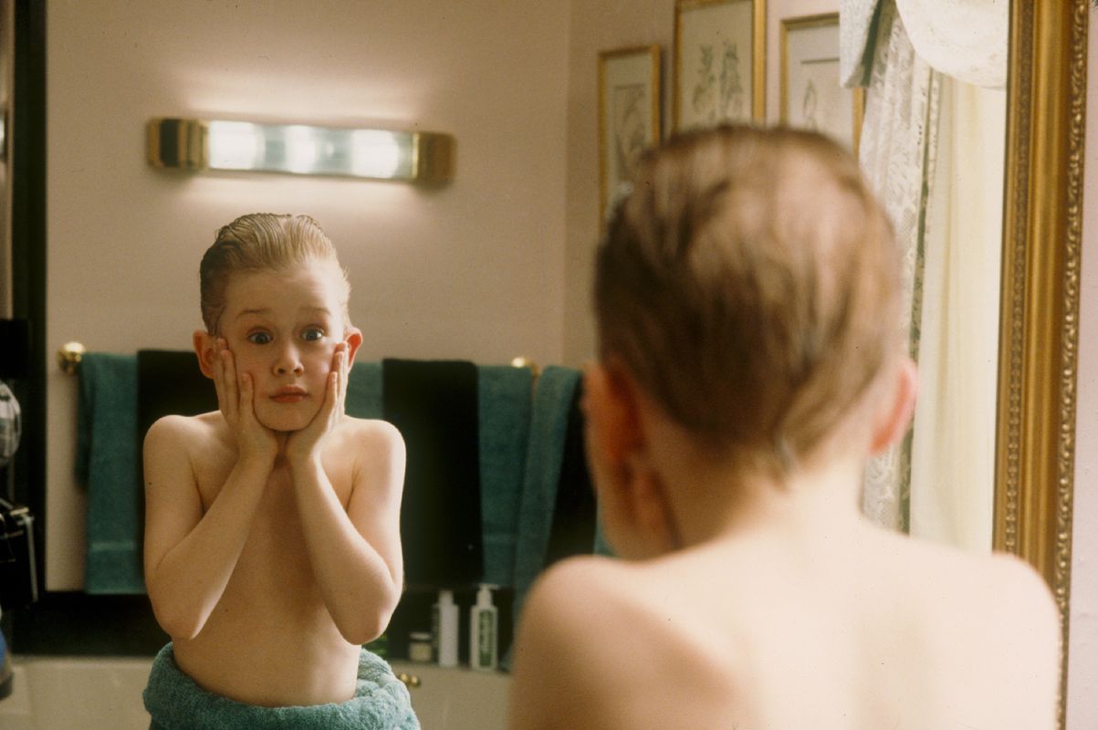 Young boy looking into the bathroom mirror with a shocked expression.