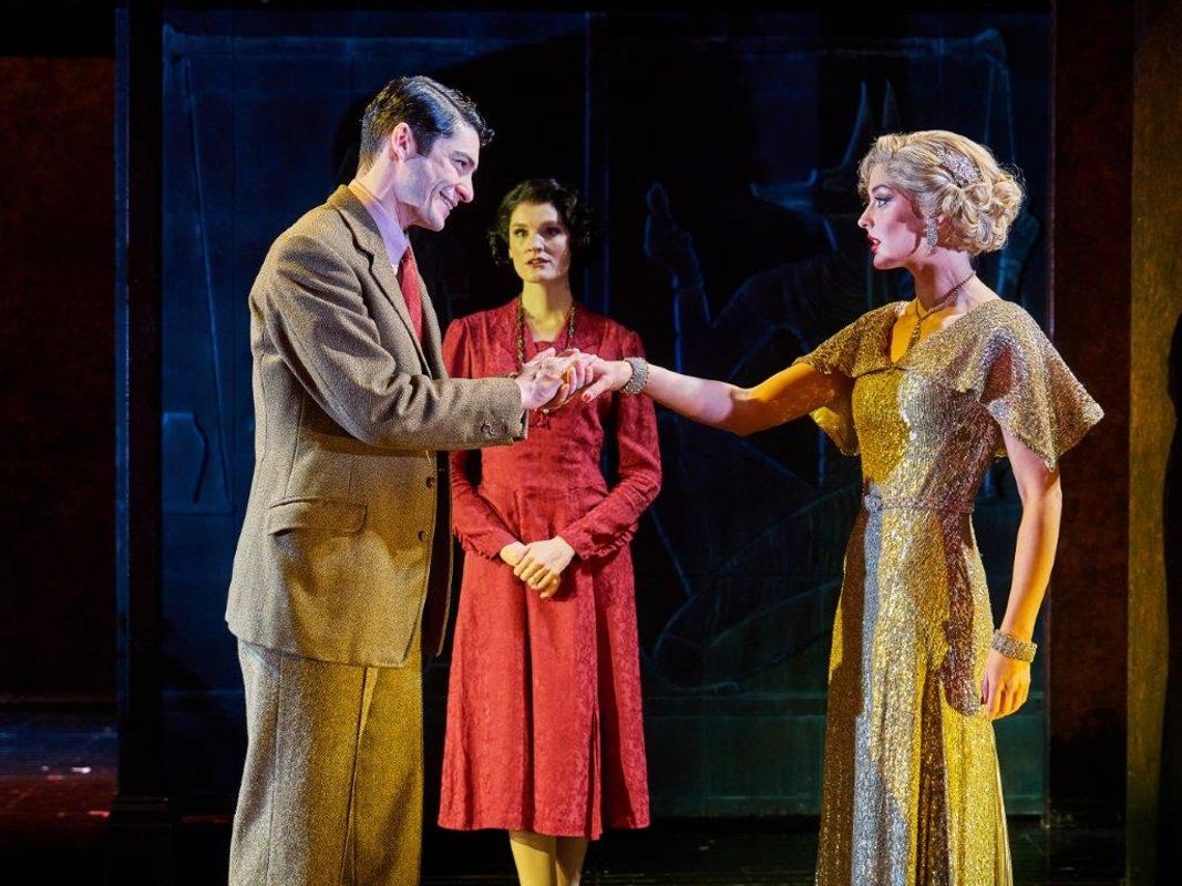 Three people, one is stood back, The other two are stood facing each other and one has taken the other one's hand