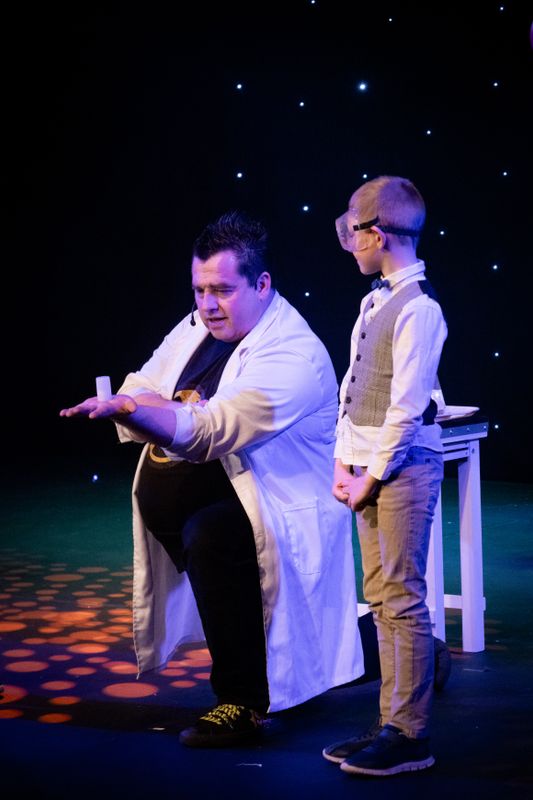 A person crouches down next to a young person wearing goggles.