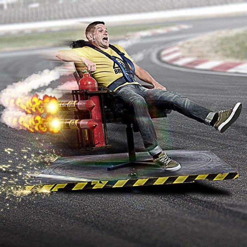 A person sits in an office chair with two rockets on the side.