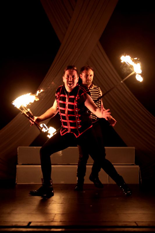 Two performers hold fire sticks.