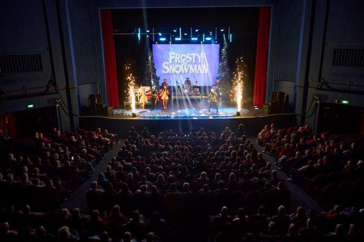 The audience look at the stage with Frosty the Snowman on the backdrop.