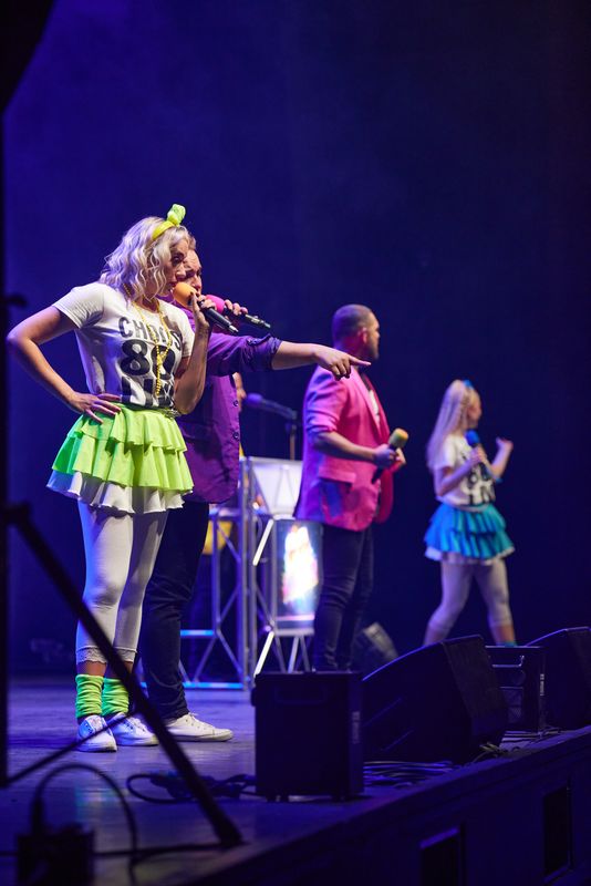 A person wearing a purple blazer points to an audience member.