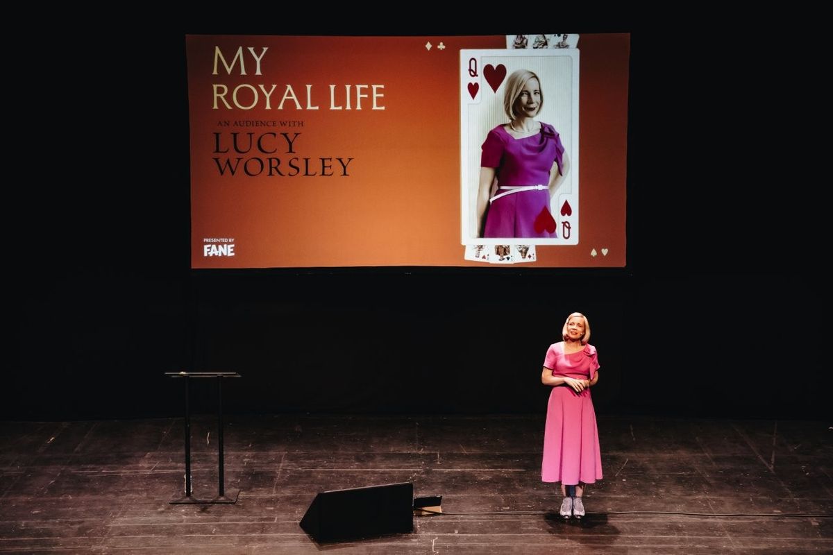 Lucy Worsley talking on stage. She is wearing a pink dress.