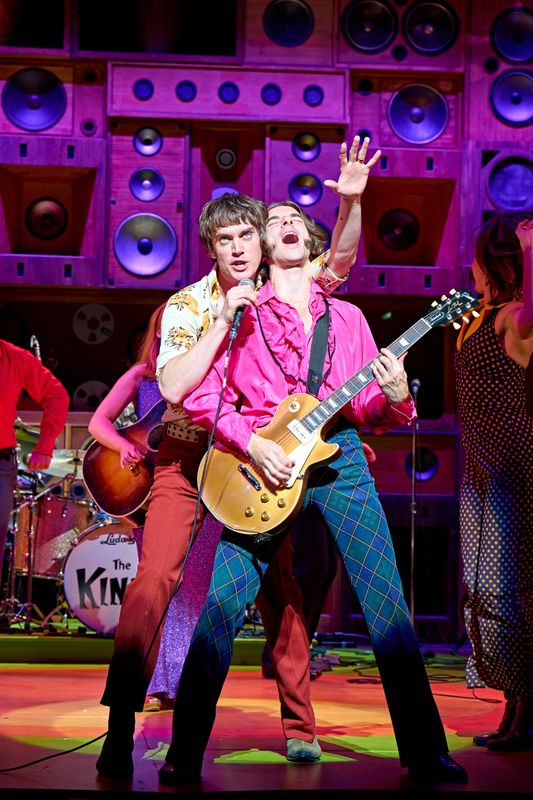 A person playing guitar plays out with the lead singer directly behind him.