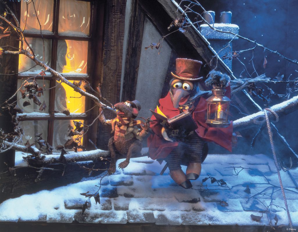 Two puppets are sat on a snowy rooftop with a lantern and a book