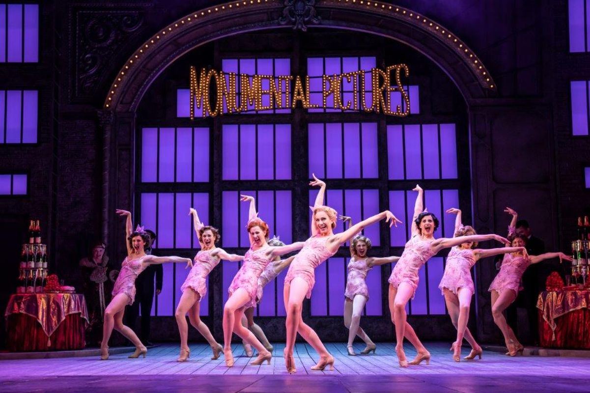 Group of women dancers all standing in the same pose with their arms out