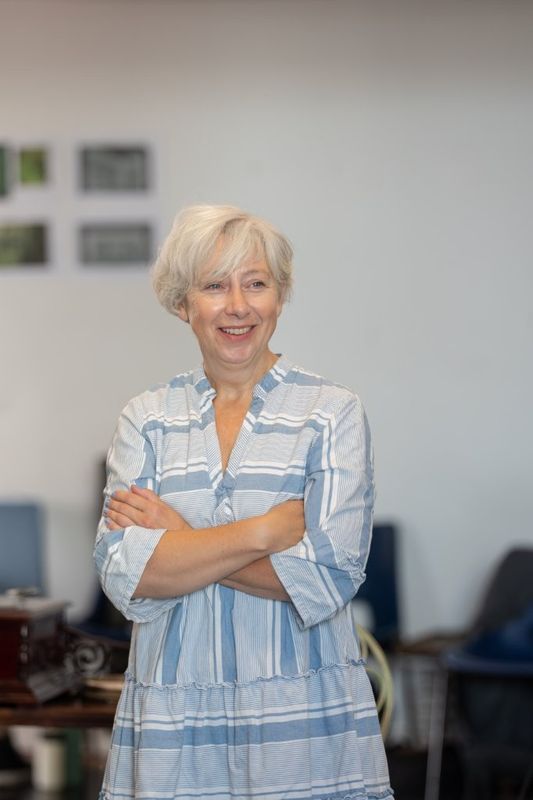 A woman is stood smiling with her arms folded