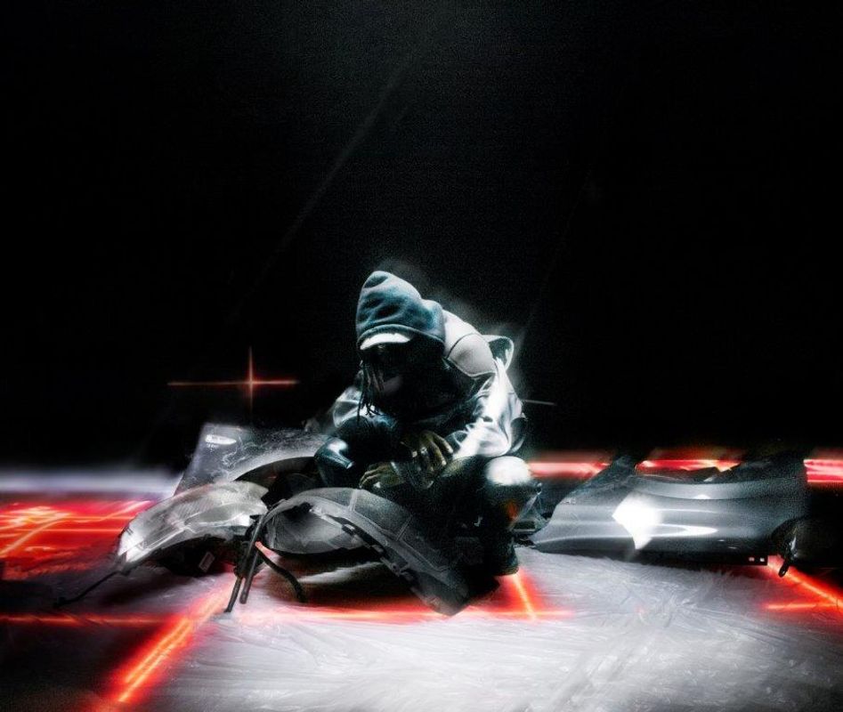 A hooded person crouches down surrounded by square red lighting.