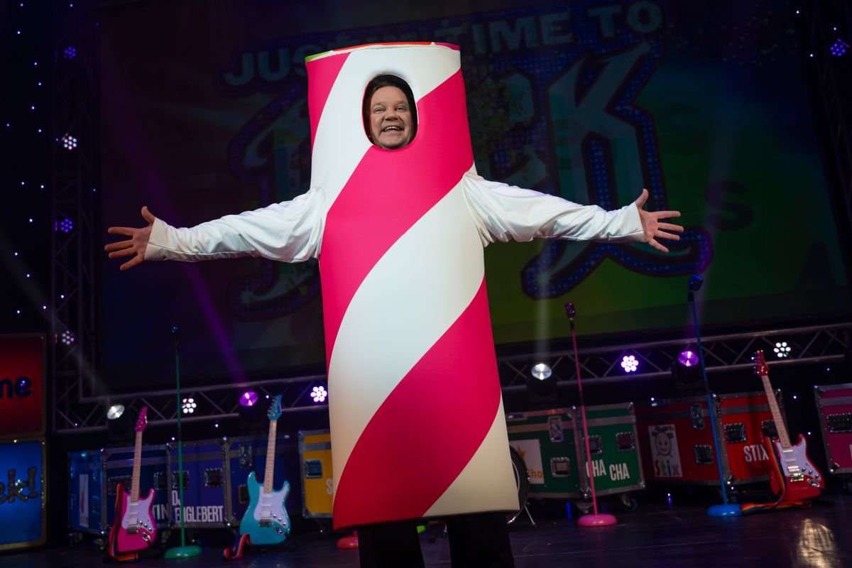 Justin stands in a red and white striped tube costume with his arms outstretched.