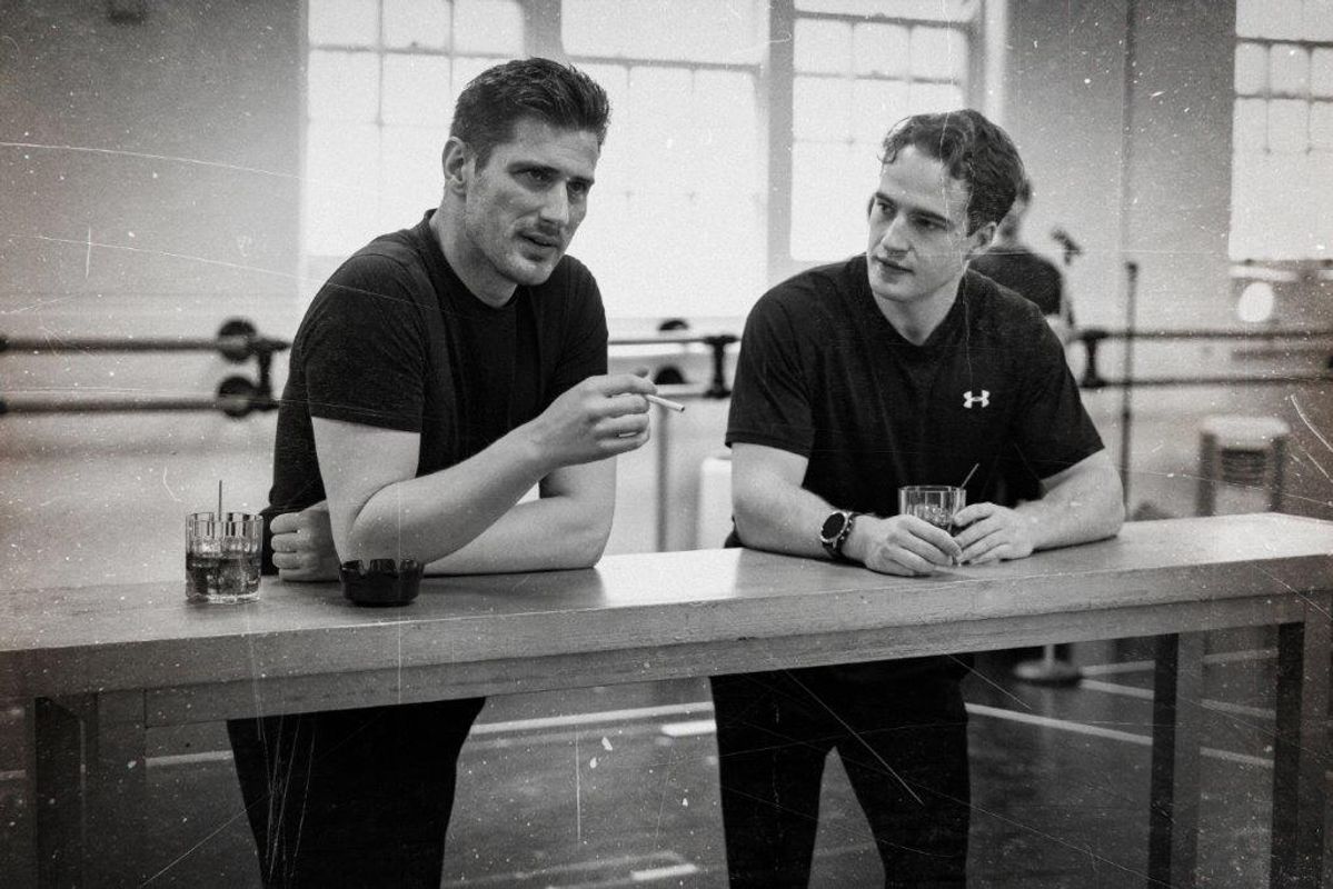 Black and white image of cats members rehearsing for Jersey boys. They are all wearing black and in a rehearsal studio