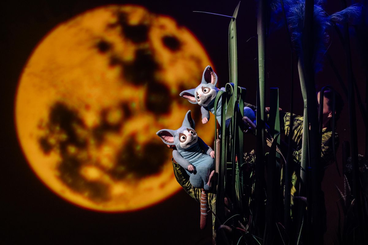 Two little creatures hanging on a stem and a giant moon is in the background