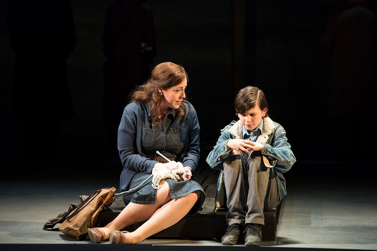 An older person sits next to a younger person on a step.