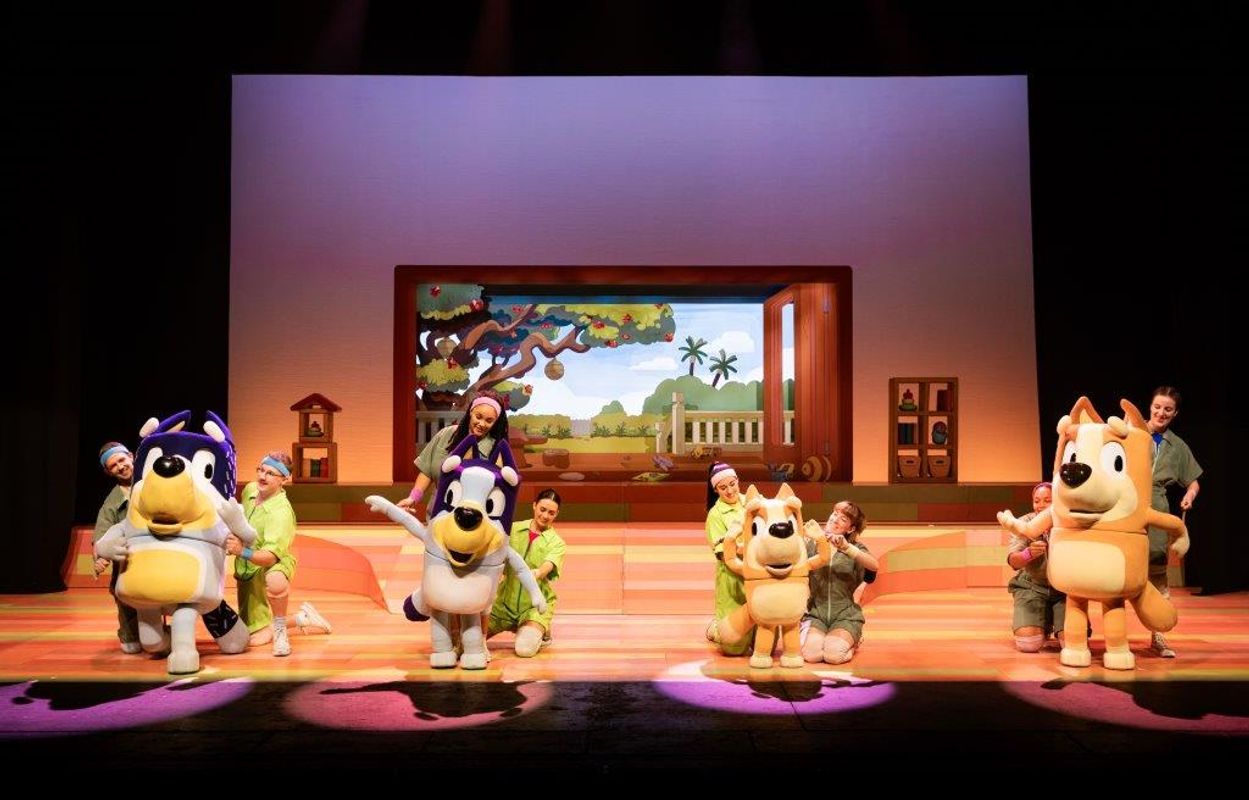 Bluey, Bingo, Mum and Dad stand in spotlights.