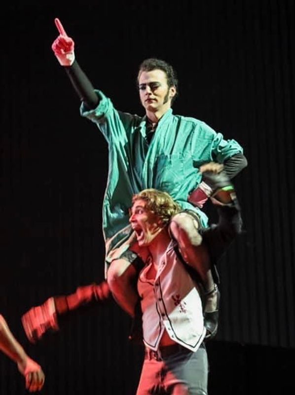 One person is sat on another persons shoulders, they look to be walking around on stage