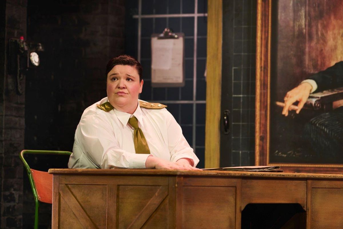 A person sat at a desk in a white shirt and gold tie